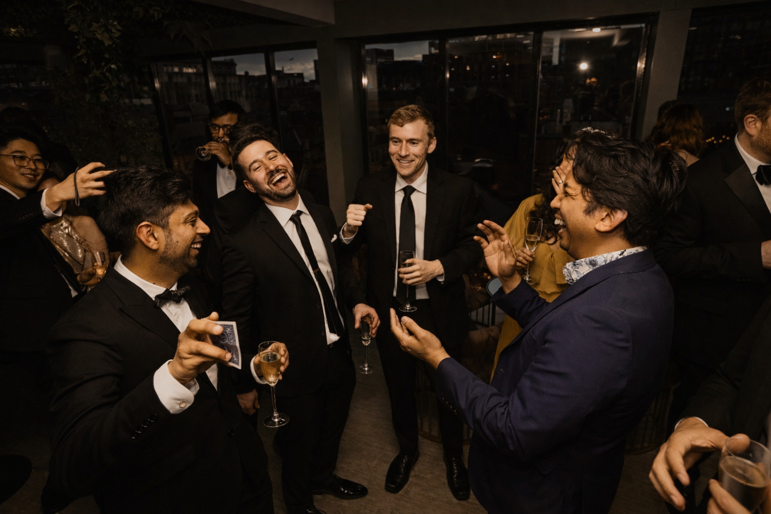 Magician performing at a corporate event, guests in black tie laughing